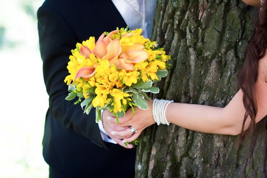 Young married couple holding hands with  wedding bouquet