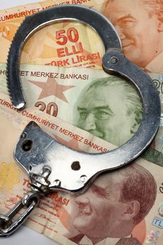 Turkish liras bills and handcuffs close up. Financial Crime and Corruption 