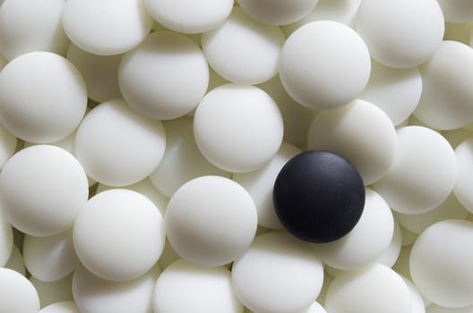 A black go stone lying on a pile of white ones. Go is a traditional Asian strategy game. It is considered to be of the oldest games in the world.