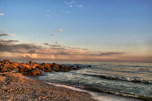 sunset by the sea in the background of the breakwater of boulders