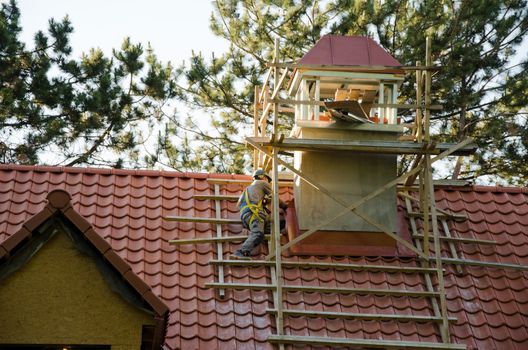 worker men with helmet covering roof with tiles. construction industry detail.