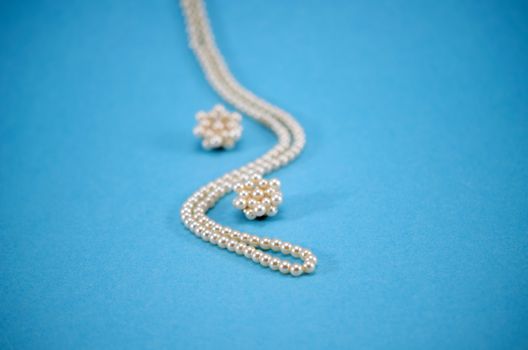 pearl jewelry beads necklace earring decoration on blue background.