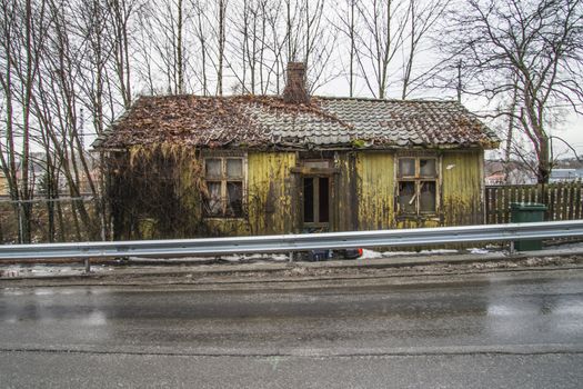 the nature has taken over, it grows weeds, wilderness, shrubs and bushes along the walls and roof of the house, the image is shot in december in a street in Halden called "river street"