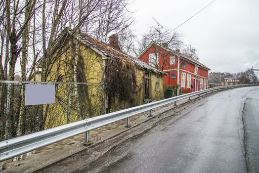 the nature has taken over, it grows weeds, wilderness, shrubs and bushes along the walls and roof of the house, the image is shot in december in a street in Halden called "river street"