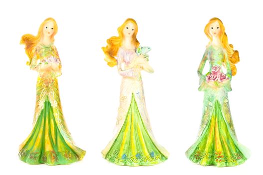 Three pretty lady statues all dressed up and holding flowers; isolated on white background.