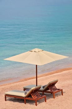 Sea beach with the two beach beds and the beach umbrella