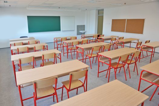 A large, empty classroom with wooden chairs.