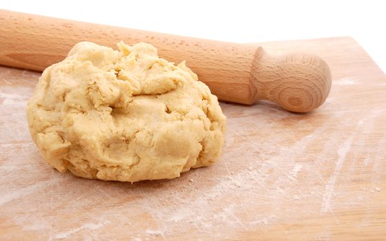 Wooden rolling pin and a fresh ball of pastry ready to be rolled out on a floured board