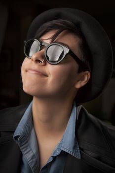 Ethnic Mixed Girl Wearing Sunglasses Against a Dark Background.