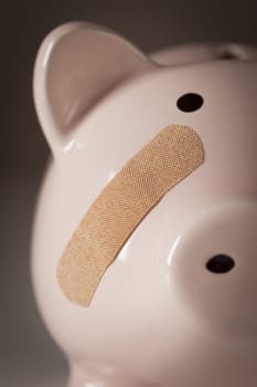 Piggy Bank with Bandage on Face on Dramatic Gradated Background.