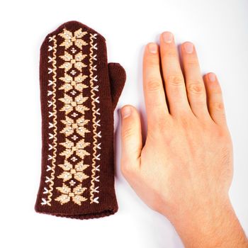 Brown woolen knitted mitten and hand on white background