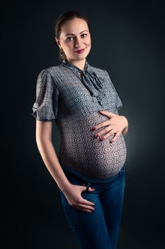 Studio shot of pregnant woman in blouse and jeans