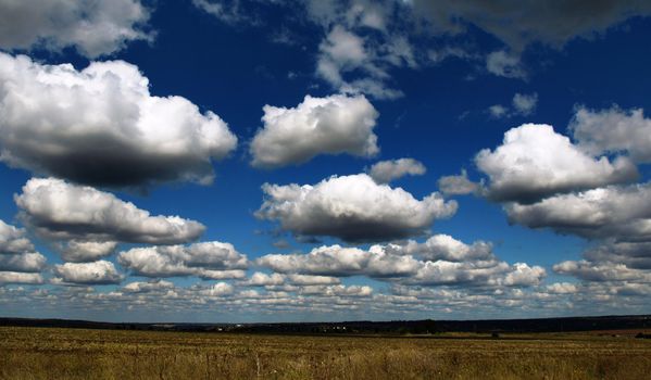 Clouds over the field against blue sky background