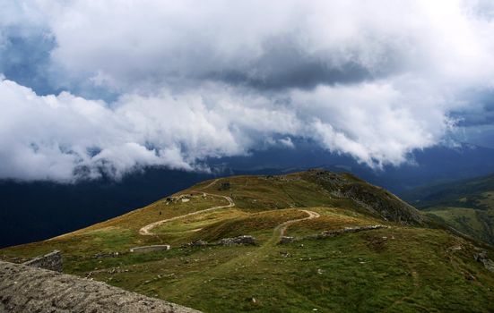 Hiking trail in mountains under low clouds