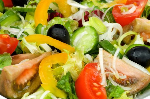 Background of Vegetable Salad with Tomatoes, Yellow Bell Pepper, Leek, Black Olive, Cucumber, Lettuce and Olive Oil closeup