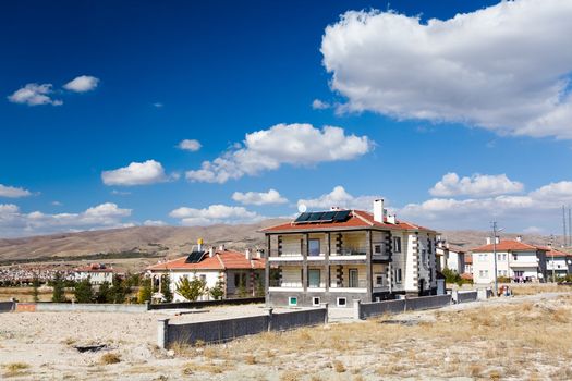 Houses with solar panels on red roofs under blue sky