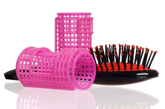 Pink hair curlers and hairbrush isolated on white background