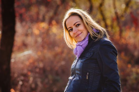 Portrait of happy beautiful young pregnant woman in autumn forest