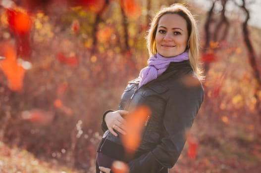 Portrait of happy beautiful young pregnant woman in autumn forest