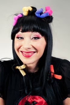 Funny portrait of young woman with curlers on her head