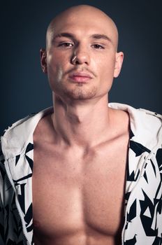 Portrait of naked athletic man posing over gray background