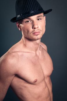Studio portrait of young bald muscular man with black hat