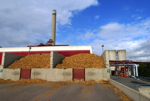 bio power plant with storage of wooden fuel against blue sky