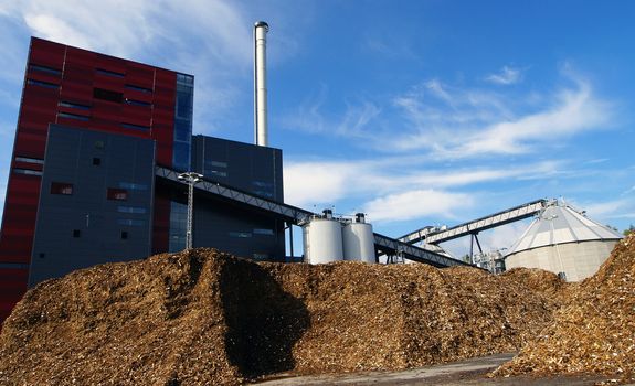 bio power plant with storage of wooden fuel against blue sky