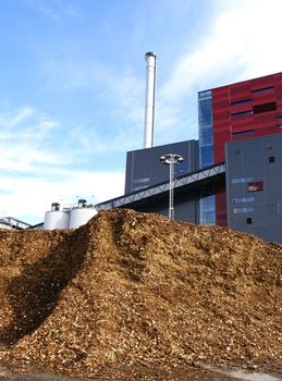 bio power plant with storage of wooden fuel against blue sky