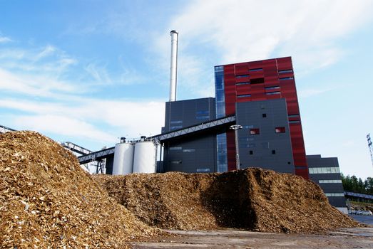 bio power plant with storage of wooden fuel against blue sky