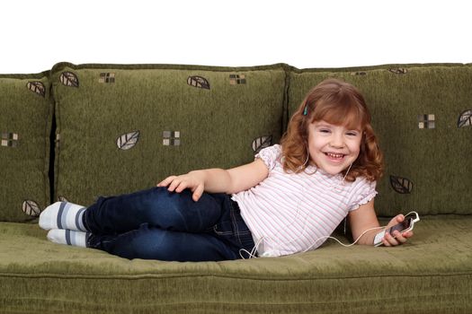 happy little girl lying on bed and listening music on phone