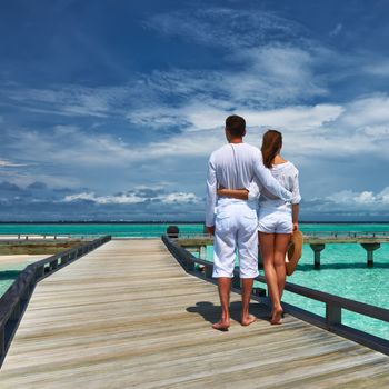 Couple on a tropical beach jetty at Maldives