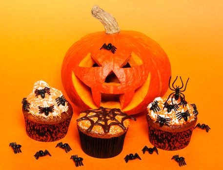 Halloween cupcakes with decoration over orange background