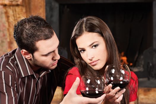 Young couple drinking wine near fireplace