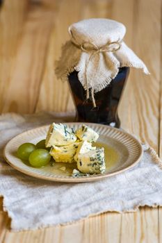Rustic jam pot, plate of blue mold camembert cheese and grapes standing on wooden table
