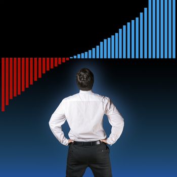 Backside of a business man in black business trousers and white business shirt who is looking to a increasing graph with a blue-black background