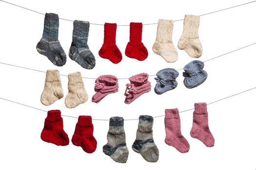 Blue, red, pink and white babysocks on a line in front of a white background