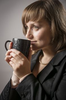 Young woman in black jacket drinking from a cup