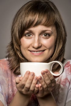 Young woman enjoying tea or coffee in a white cup