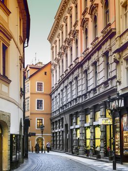 Narrow street with shops in Prague, a street with cobblestones in January in an evening atmosphere.