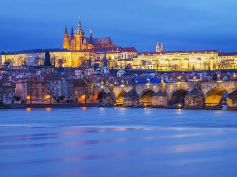 View to illuminated Prague with Charles Bridge, Hradcany Castle and Vitus in the evening at January 