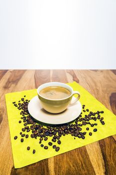 Cup of coffee on a wooden table and beans on a green serviette