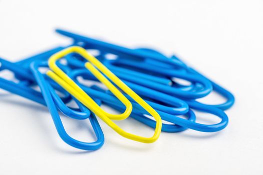 A yellow paper clip on a white background with lots of blue