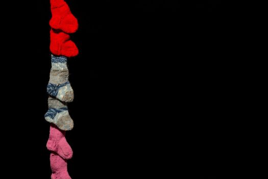 Three pairs of baby socks in front of a black background