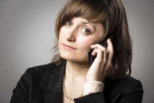 Business woman in black suit and pearls phone