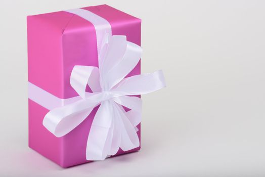 gift with white ribbon in purple paper on white underground