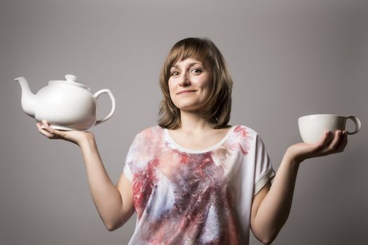 Young brunette woman with colored clothes holding a white cup and a white tea tin