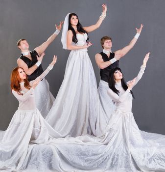 Actors in the wedding dress dancing. On a gray background in full length.