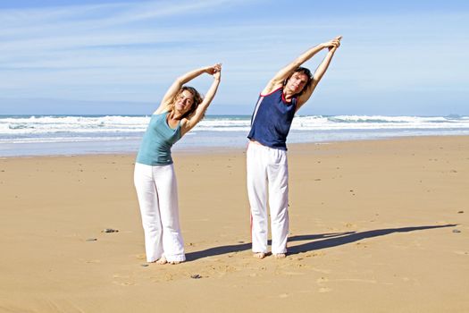 Couple doing yoga excersises at the beach