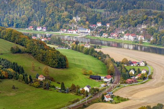 Landscape with colored trees, houses and river named Elbe in saxony swiss in autumn